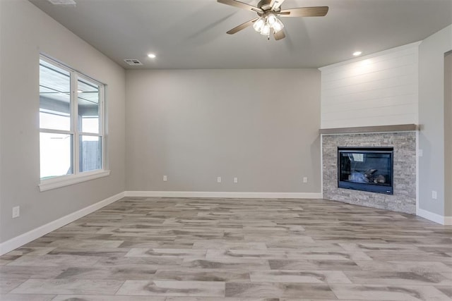 unfurnished living room featuring ceiling fan, a fireplace, and light wood-type flooring