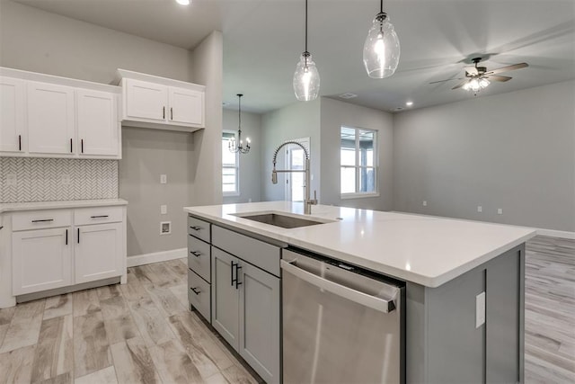 kitchen featuring white cabinetry, stainless steel dishwasher, a kitchen island with sink, and sink