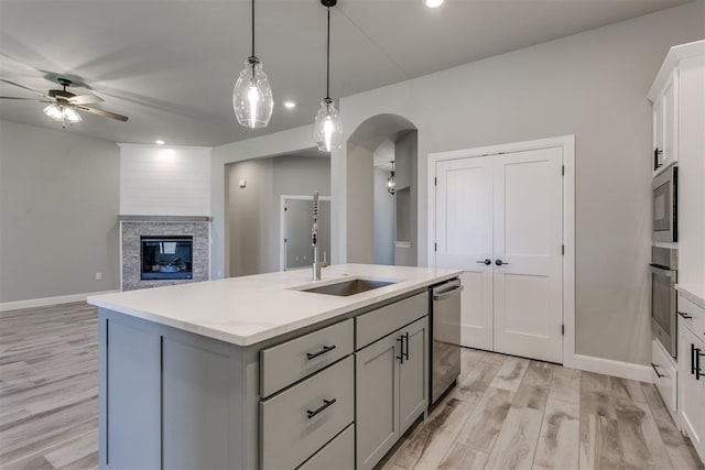 kitchen with ceiling fan, sink, an island with sink, light hardwood / wood-style floors, and appliances with stainless steel finishes