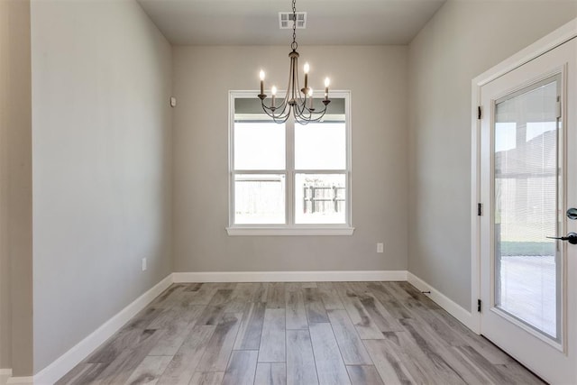 unfurnished dining area with light hardwood / wood-style floors and a notable chandelier