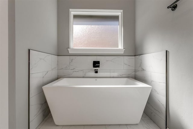 bathroom with a bathing tub and tile walls