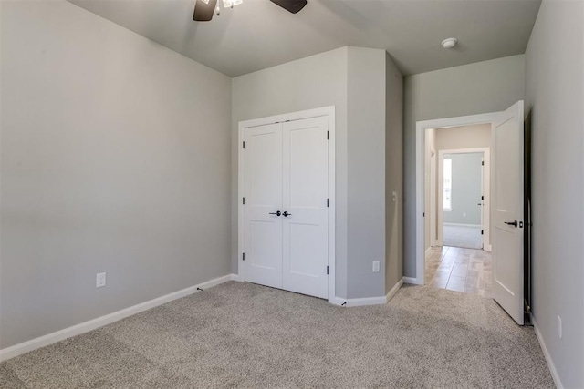 unfurnished bedroom with a closet, light colored carpet, and ceiling fan