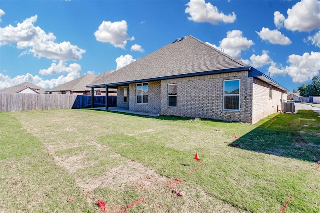 rear view of house featuring central AC unit and a lawn