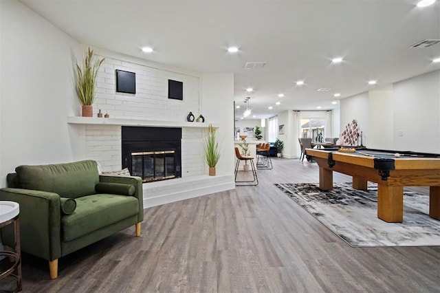 rec room featuring wood-type flooring, pool table, and a brick fireplace