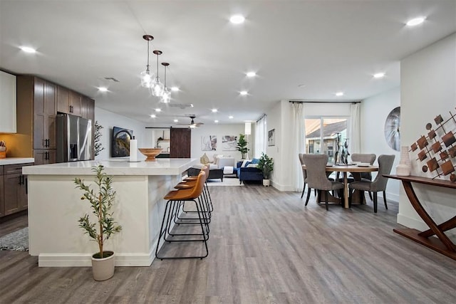 kitchen featuring hardwood / wood-style flooring, stainless steel fridge, a barn door, decorative light fixtures, and a kitchen island