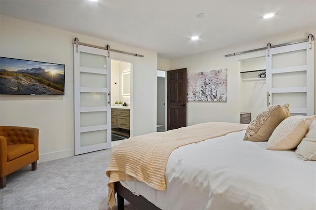 carpeted bedroom featuring a barn door and ensuite bath