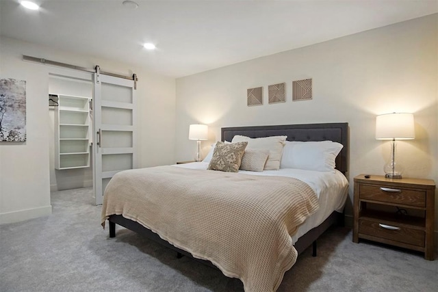 bedroom with carpet flooring, a walk in closet, a closet, and a barn door