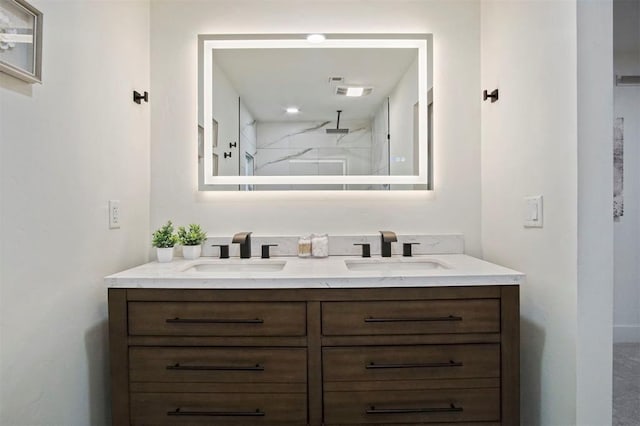 bathroom with a tile shower and vanity