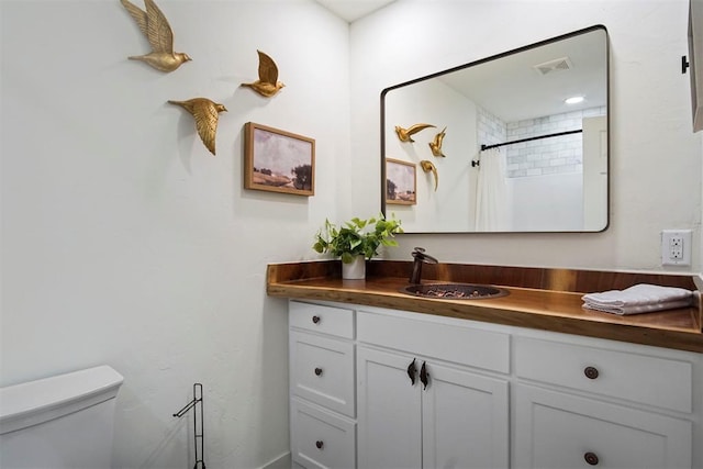 bathroom with curtained shower, vanity, and toilet