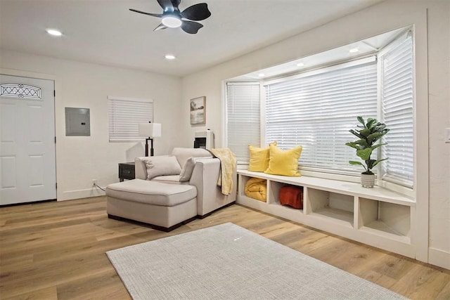 living area featuring hardwood / wood-style flooring, ceiling fan, and electric panel