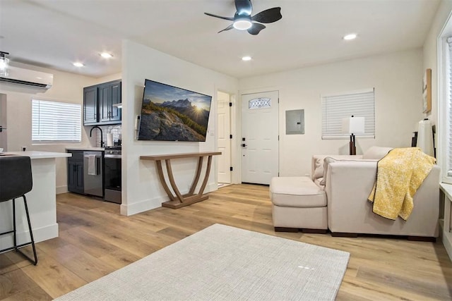 living room featuring light wood-type flooring, electric panel, a wall mounted AC, and ceiling fan