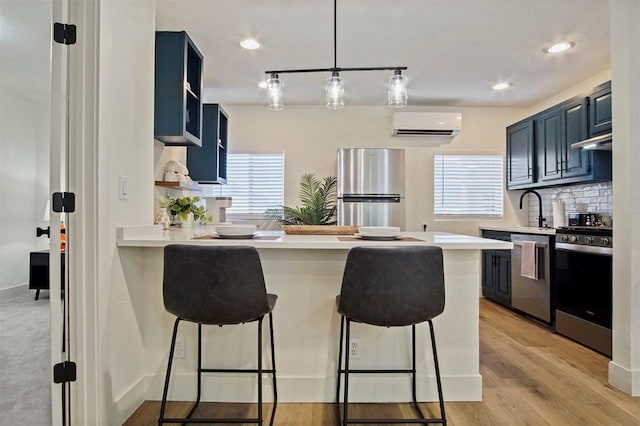 kitchen featuring a breakfast bar, blue cabinets, kitchen peninsula, and appliances with stainless steel finishes