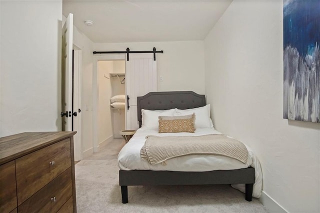 carpeted bedroom featuring a barn door, a spacious closet, and a closet