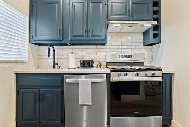 kitchen with decorative backsplash, stainless steel appliances, blue cabinets, sink, and range hood