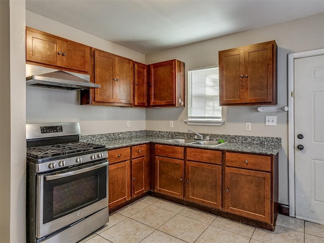 kitchen with light tile patterned floors, range hood, stainless steel range with gas cooktop, and sink