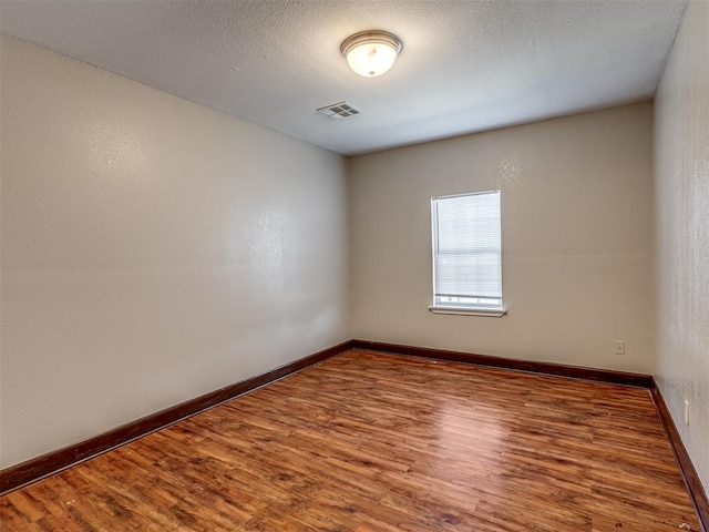 spare room featuring wood-type flooring and a textured ceiling