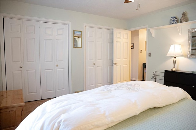 carpeted bedroom with two closets and a ceiling fan