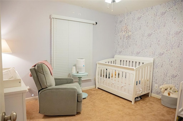 carpeted bedroom with a crib and baseboards