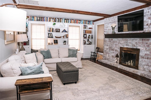 living room featuring visible vents, a brick fireplace, beam ceiling, and plenty of natural light