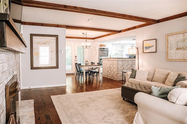 living room featuring a chandelier, dark wood-style flooring, baseboards, a brick fireplace, and beam ceiling