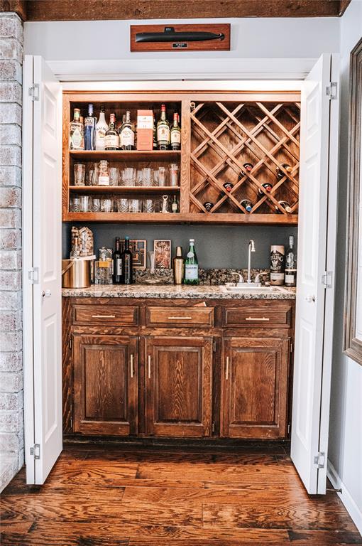 bar featuring dark wood-style flooring, indoor wet bar, and a sink