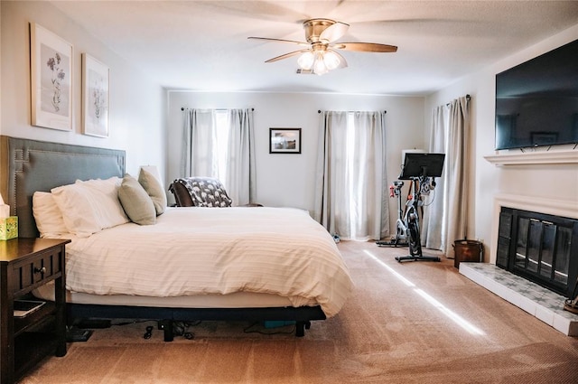 bedroom with a ceiling fan, carpet, and a glass covered fireplace