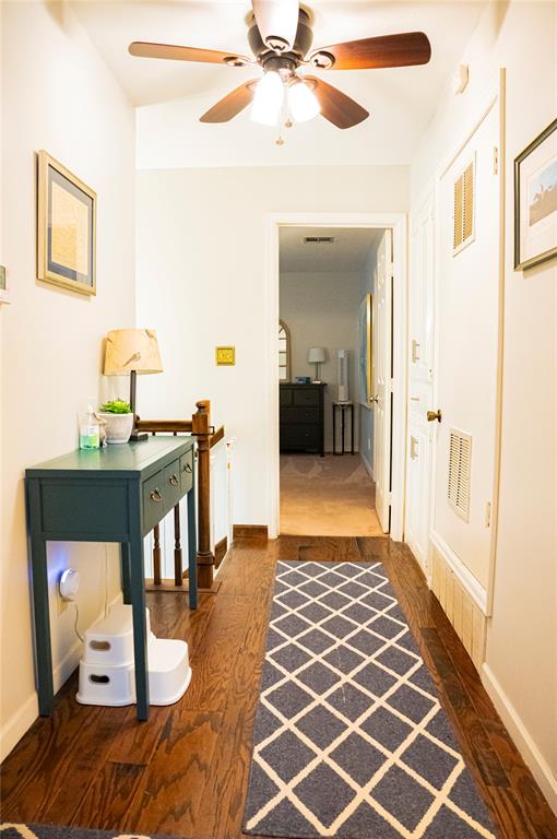 hall with baseboards, visible vents, and dark wood finished floors