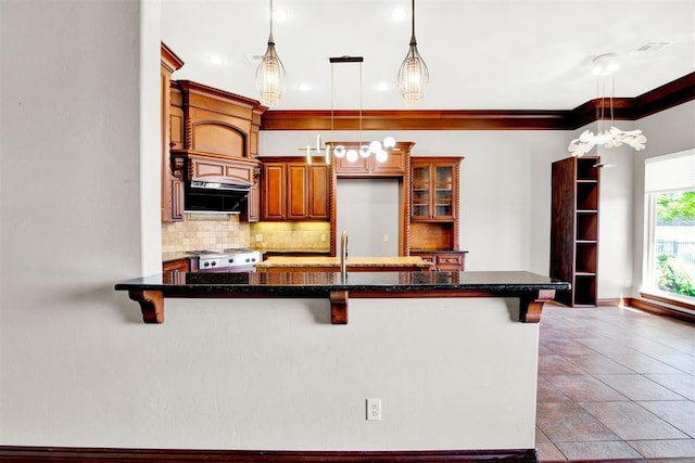 kitchen with a breakfast bar area, tasteful backsplash, decorative light fixtures, and ornamental molding