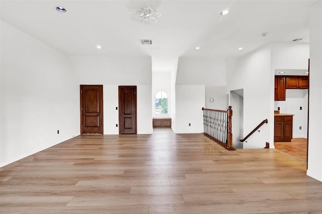 unfurnished room with light wood-type flooring and a high ceiling