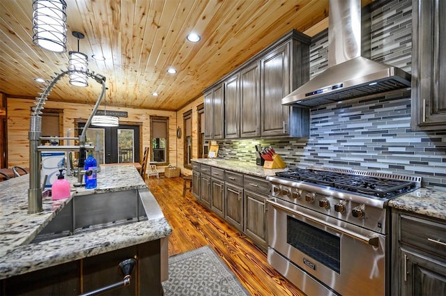 kitchen featuring wall chimney exhaust hood, dark brown cabinetry, high end stainless steel range oven, and dark wood-type flooring