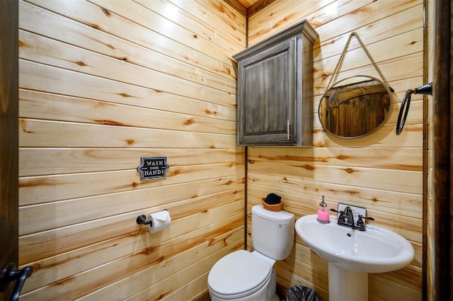 bathroom featuring sink, toilet, and wood walls