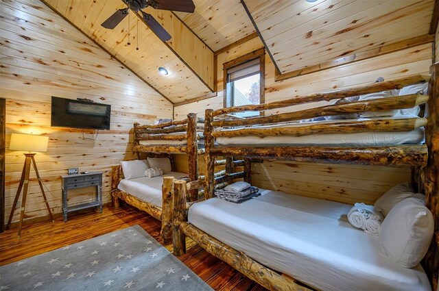 bedroom with wood walls, vaulted ceiling, dark hardwood / wood-style floors, ceiling fan, and wood ceiling