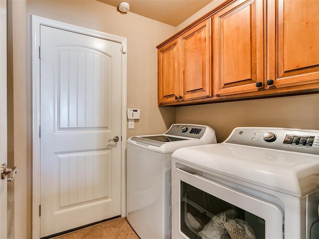 washroom featuring washer and clothes dryer, light tile patterned floors, and cabinets