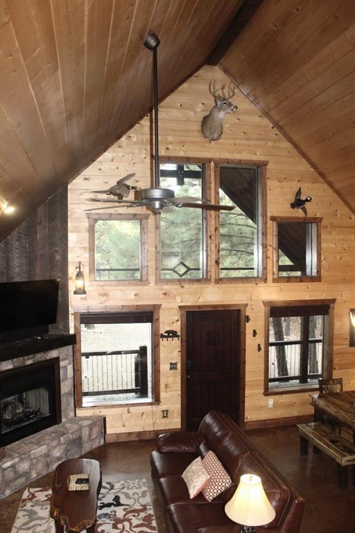 living room with beam ceiling, wood ceiling, a fireplace, and wooden walls