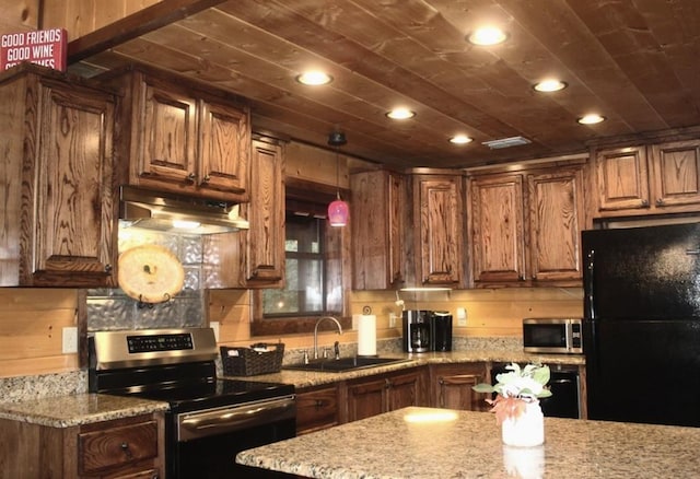 kitchen with hanging light fixtures, light stone counters, sink, and stainless steel appliances