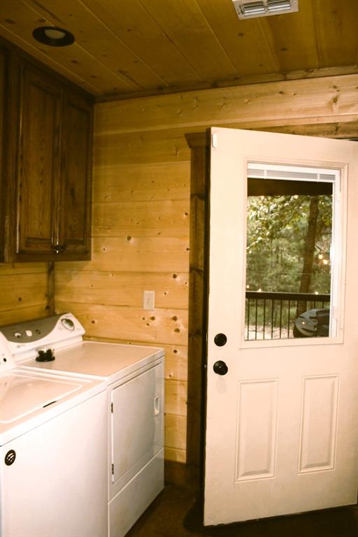 laundry area featuring wood walls, cabinets, separate washer and dryer, and wood ceiling