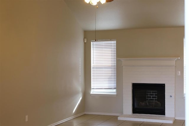 unfurnished living room with a brick fireplace, ceiling fan, and light tile patterned flooring