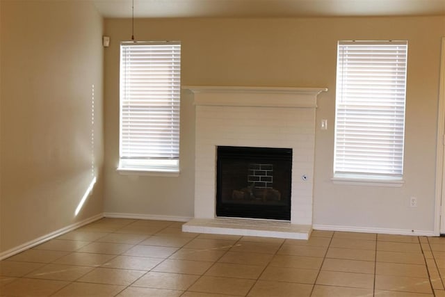 unfurnished living room featuring a brick fireplace and light tile patterned floors