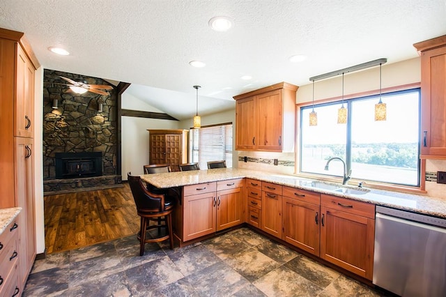 kitchen featuring kitchen peninsula, stainless steel dishwasher, sink, lofted ceiling, and a breakfast bar area