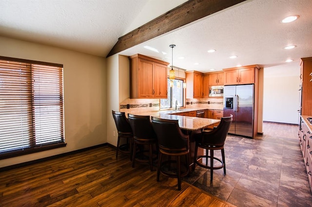 kitchen featuring kitchen peninsula, appliances with stainless steel finishes, dark hardwood / wood-style floors, and hanging light fixtures