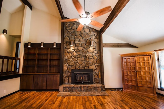 unfurnished living room with a wood stove, ceiling fan, dark wood-type flooring, and lofted ceiling with beams