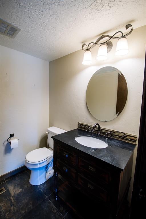 bathroom with vanity, toilet, and a textured ceiling