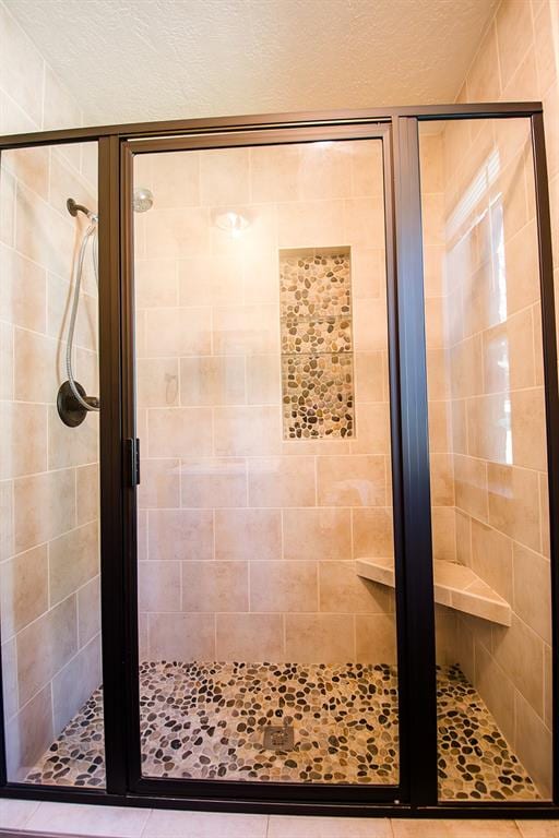 bathroom featuring tile patterned flooring, a shower with door, and a textured ceiling