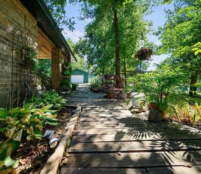 view of patio featuring a garage, an outbuilding, and a wooden deck