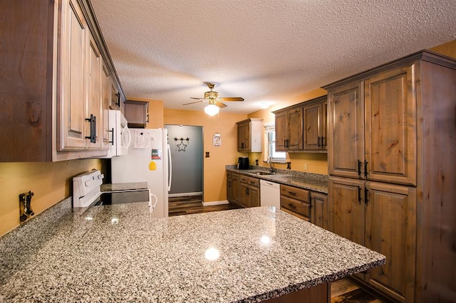 kitchen featuring kitchen peninsula, light stone counters, a textured ceiling, white appliances, and ceiling fan