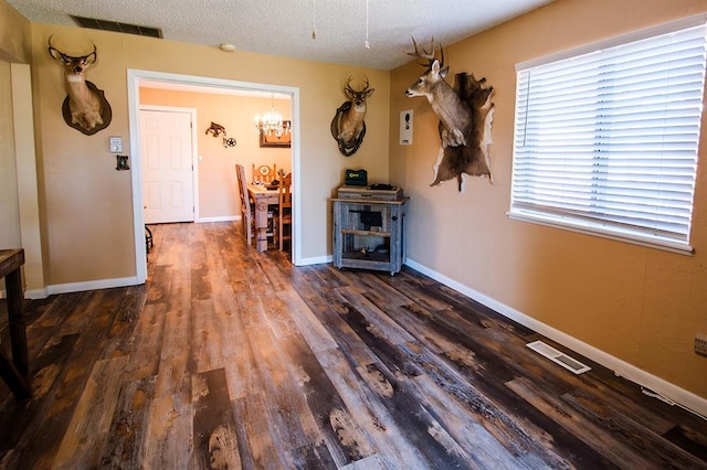 interior space featuring dark hardwood / wood-style flooring, a chandelier, and a textured ceiling