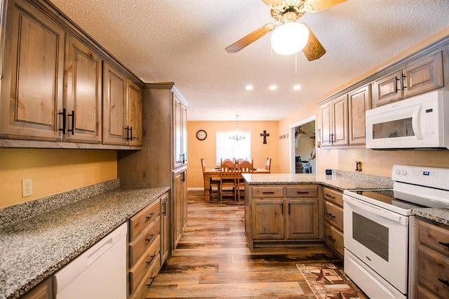 kitchen with a textured ceiling, ceiling fan with notable chandelier, dark hardwood / wood-style floors, and white appliances