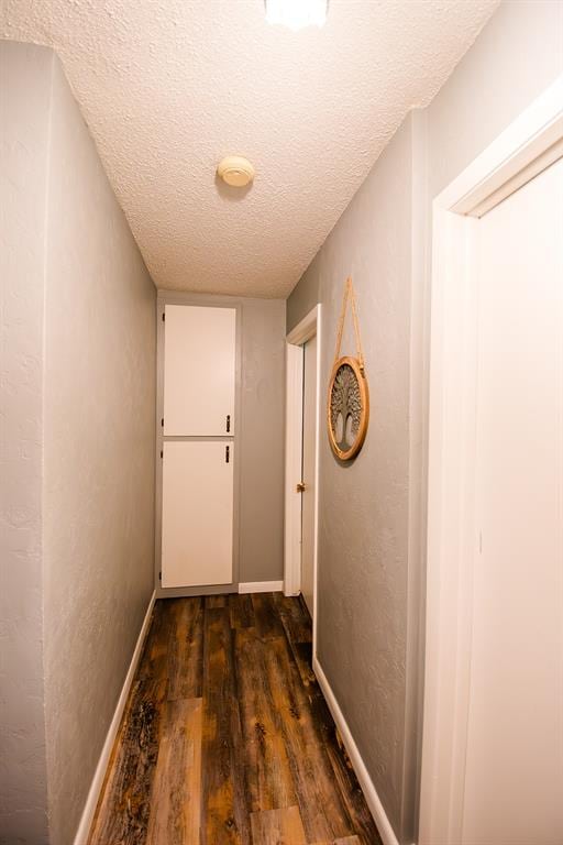 hall with a textured ceiling and dark wood-type flooring