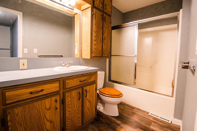 full bathroom featuring combined bath / shower with glass door, wood-type flooring, vanity, and toilet