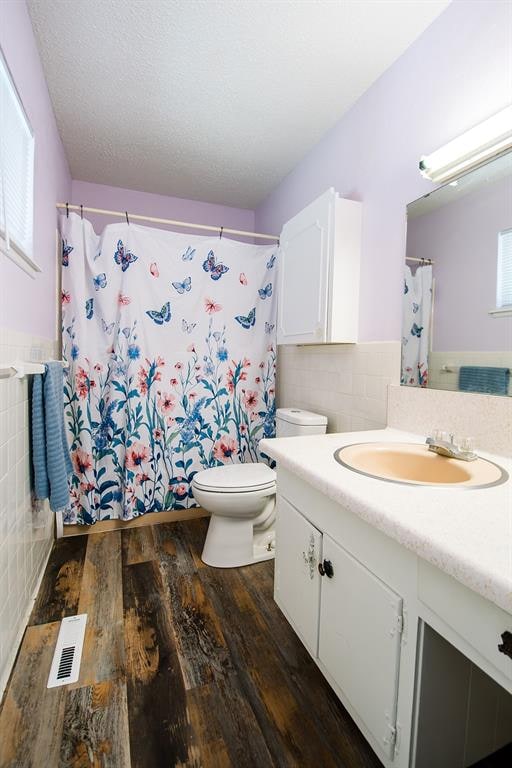 bathroom featuring a shower with curtain, toilet, vanity, tile walls, and hardwood / wood-style flooring